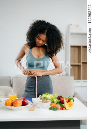 Smiling woman measuring waist, holding green apple with fruits, veggies, 122962741