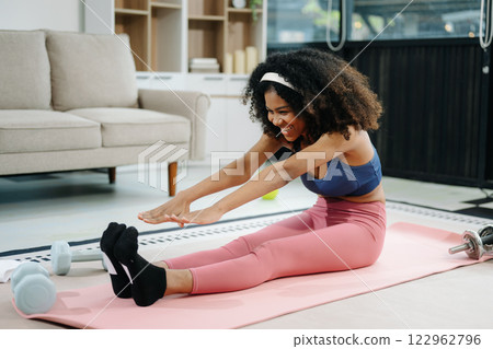 Woman Doing Yoga and Watching Online Tutorials on Laptop, Training in Living Room at home Woman Doing Yoga and Watching Online Tutorials on Laptop, Training in Living Room at home 122962796