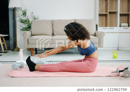 Woman Doing Yoga and Watching Online Tutorials on Laptop, Training in Living Room at home 122962799