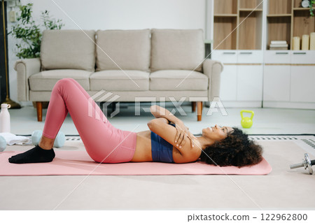Woman Doing Yoga and Watching Online Tutorials on Laptop, Training in Living Room at home Woman Doing Yoga and Watching Online Tutorials on Laptop, Training in Living Room at home 122962800