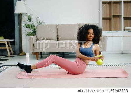 A young woman practices yoga and stretching with a mat and gym props, showcasing wellness, motivation, A young woman practices yoga and stretching with a mat and gym props, showcasing wellness, motivation, 122962803