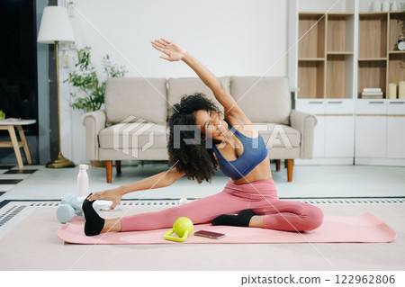 Woman Doing Yoga and Watching Online Tutorials on Laptop, Training in Living Room at home Woman Doing Yoga and Watching Online Tutorials on Laptop, Training in Living Room at home 122962806