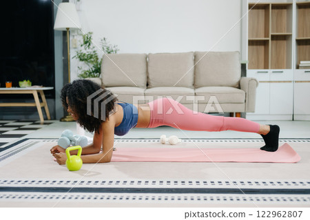 A young woman practices yoga and stretching with a mat and gym props, showcasing wellness, motivation, 122962807