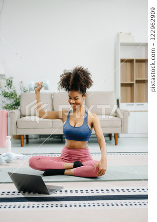Woman Doing Yoga and Watching Online Tutorials on Laptop, Training in Living Room at home 122962909