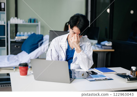 Doctor analyzing patient data on tablet in clinical lab. Medical professional in hospital with laptop, blood samples 122963043