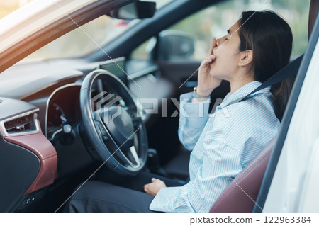woman feeling sleepy and yawn during drive car long time. Asian girl tired and fatigue having headache after driving car in traffic jam. Sleep, stretching and safety concept 122963384