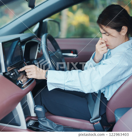 Asian woman hold nose because bad smell after turn on air conditioning in car. Woman driving car with broken air conditioning in hot summer weather. Businesswoman driver is tired, overheat and stress 122963403