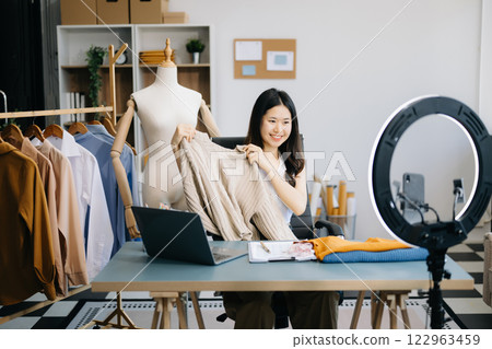 Fashion blogger concept, Young women selling clothes on video streaming.Startup small business SME, using smartphone or tablet taking receive and checking Fashion blogger concept, Young women selling clothes on video streaming.Startup small business SME, using smartphone or tablet taking receive and checking 122963459