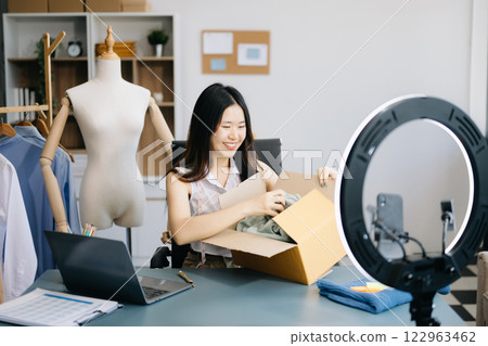Fashion blogger concept, Young women selling clothes on video streaming.Startup small business SME, using smartphone or tablet taking receive and checking Fashion blogger concept, Young women selling clothes on video streaming.Startup small business SME, using smartphone or tablet taking receive and checking 122963462