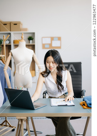 Asian tailor woman working on clothes in tailoring atelier. beautiful young female fashion designer smile and after success in studio 122963477