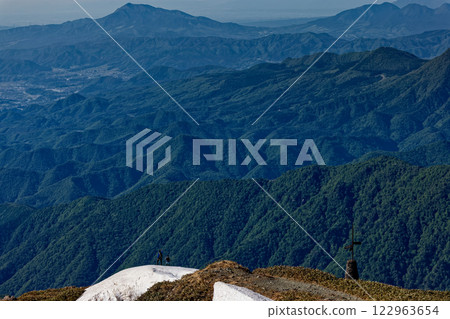 Climbers walking just below the summit of Mt. Tanigawa in early summer and a view of Mt. Komochi 122963654