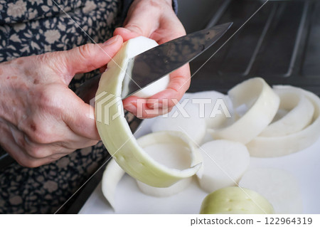 Senior woman's hands peeling radish with a knife 122964319