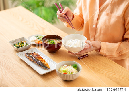 Middle-aged woman eating Japanese breakfast Middle-aged woman eating Japanese breakfast 122964714