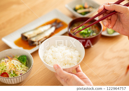 Middle-aged woman eating Japanese breakfast Middle-aged woman eating Japanese breakfast 122964757