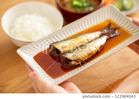 一位中年婦女正在吃煮沙丁魚作為日式早餐 122964843