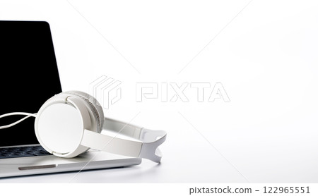 A headphones resting on a laptop, set against a bright white background A headphones resting on a laptop, set against a bright white background 122965551