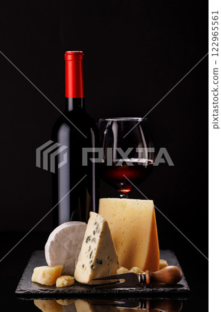A refined selection of aged cheeses presented on a board, accompanied by a glasses of wine A refined selection of aged cheeses presented on a board, accompanied by a glasses of wine 122965561