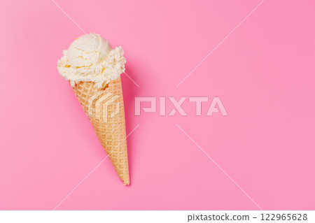 A refreshing ice cream cone set against a vibrant pink background 122965628