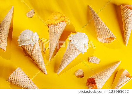 A refreshing ice cream cones set against a vibrant yellow background A refreshing ice cream cones set against a vibrant yellow background 122965632