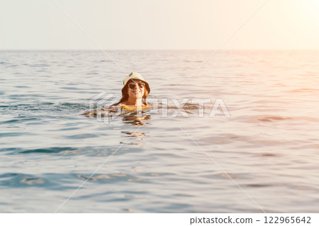 Woman Swimming Ocean Hat Summer - A woman in a hat swims in the ocean during a summer day. 122965642