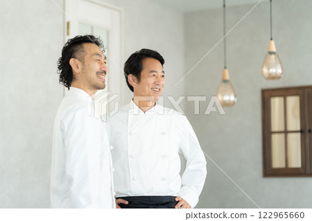 Two middle-aged chefs with their arms folded Two middle-aged chefs with their arms folded 122965660