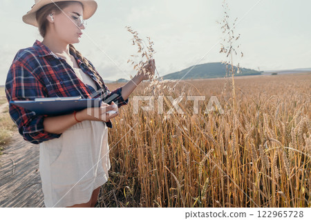 A Young Woman Examines a Wheat Field A Young Woman Examines a Wheat Field 122965728