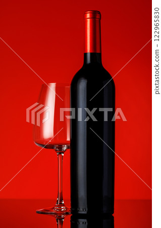 A red wine bottle, glass of wine, and corkscrew placed on a vibrant red background A red wine bottle, glass of wine, and corkscrew placed on a vibrant red background 122965830
