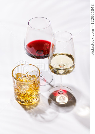 A refined composition of wine glasses filled with red and white wine, paired with a whiskey glass A refined composition of wine glasses filled with red and white wine, paired with a whiskey glass 122965848