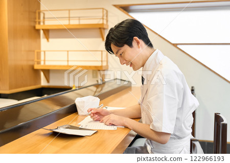 A Japanese chef doing the calculations A Japanese chef doing the calculations 122966193