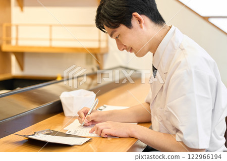 A Japanese chef doing the calculations 122966194