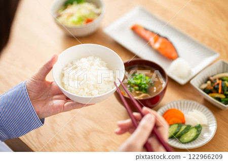 A middle-aged woman eating a Japanese breakfast of grilled salmon 122966209