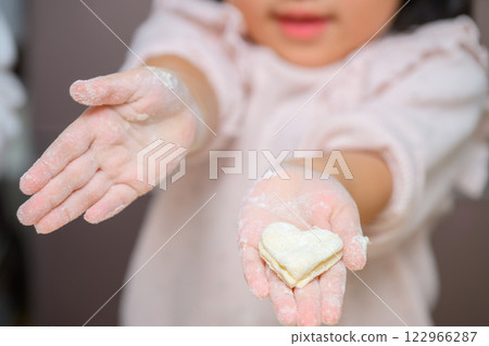 Girl making heart-shaped cookies Girl making heart-shaped cookies 122966287