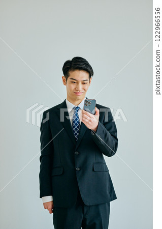 A young man in his twenties holding a smartphone 122966556