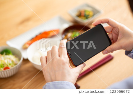 Japanese breakfast and the hand of a middle-aged woman holding a smartphone 122966672