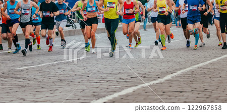large group of runners run marathon on cobblestone street large group of runners run marathon on cobblestone street 122967858