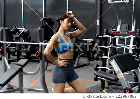 young woman is standing and resting on Wipe the sweat  an exercise machine 122967862