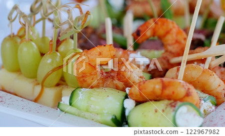Elegant catering spread displaying gourmet canapes with succulent shrimp, creamy cheese, and fresh grapes, elevating culinary experience at sophisticated events 122967982