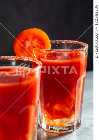 Two vegetable shaken cocktails in glass on dark grey background. Red tomato cocktail. Served with tomato slice. Vegan menu. 122968238