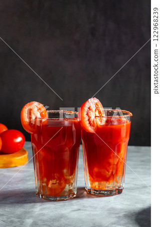 Two vegetable shaken cocktails in glass on dark grey background. Red tomato cocktail. Served with tomato slice. Vegan menu. 122968239