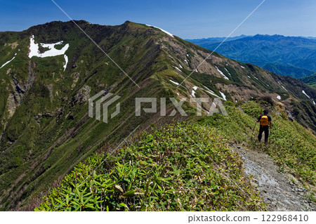 Climbers walking along the Tanigawa mountain range traverse trail near Ojikazawano-to in early summer, with a view of Mt. Tanigawa 122968410