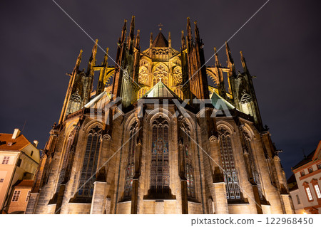 Back side of St Vitus Cathedral showcases intricate architectural features illuminated against the night sky in Prague, Czechia, revealing the craftsmanship of this historic landmark. 122968450
