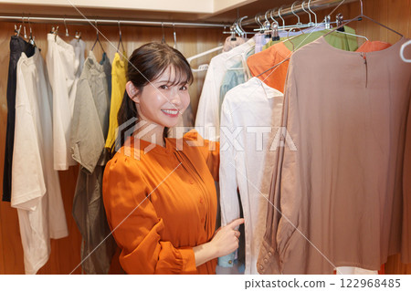 一位女士在步入式衣櫥裡挑選衣服（時尚搭配） 122968485