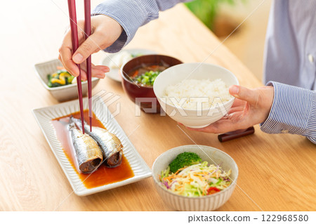 一位中年婦女正在吃煮沙丁魚作為日式早餐 122968580