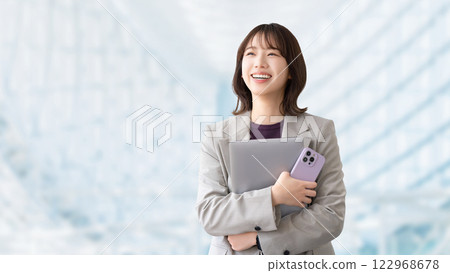 Smiling woman/businesswoman holding a computer and smartphone Smiling woman/businesswoman holding a computer and smartphone 122968678