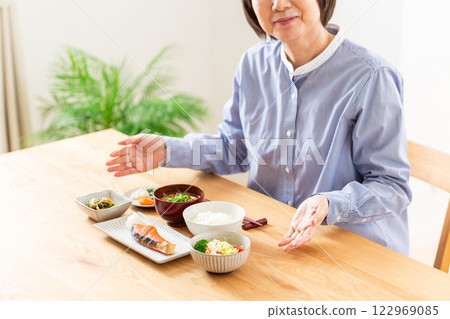 Middle-aged woman laughing in front of a Japanese breakfast 122969085