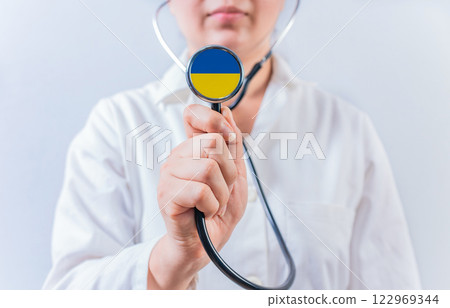Female doctor holding stethoscope with Ukraine flag. National Health System of Ukraine 122969344