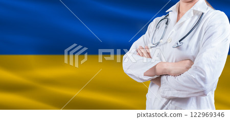 Doctor with crossed arms on Ukraine flag. Ukraine Health and Care concept. Female doctor on Ukraine flag Doctor with crossed arms on Ukraine flag. Ukraine Health and Care concept. Female doctor on Ukraine flag 122969346