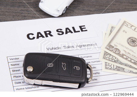 White toy car, car key, dollar banknotes and vehicle sales agreement. Inscription car sale 122969444