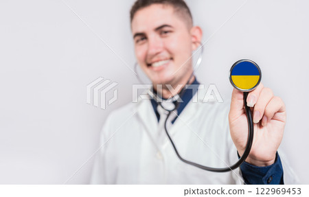 Happy doctor showing stethoscope with Ukraine flag. Ukraine National Healthcare concept Happy doctor showing stethoscope with Ukraine flag. Ukraine National Healthcare concept 122969453
