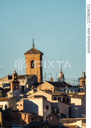 Toledo. A charming Spanish cityscape featuring a brick bell tower rising above tiled rooftops on a sunny day. Toledo. A charming Spanish cityscape featuring a brick bell tower rising above tiled rooftops on a sunny day. 122969611
